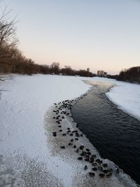 Scenic view of frozen river against clear sky during winter