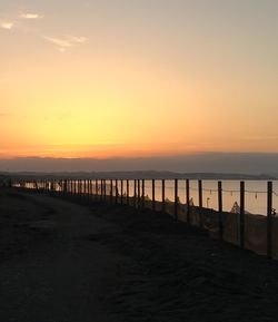 Pier over sea against sky during sunset