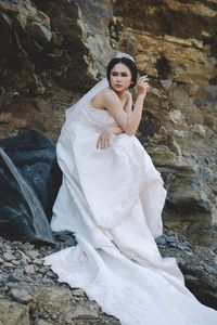 Young beautiful bride sitting against rock formation