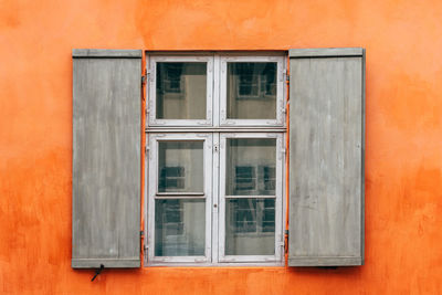 Old wooden window shutters of an european house with orange painted facade, vintage background.