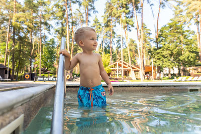 Cute boy looking away while standing in swimming pool