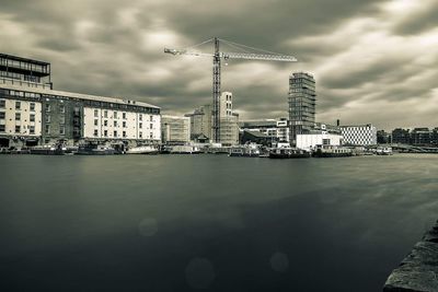 City at waterfront against cloudy sky