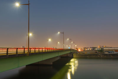 Illuminated bridge over river against sky
