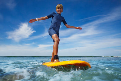 Full length of woman jumping in sea against sky