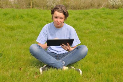 Young man using mobile phone while sitting on grass