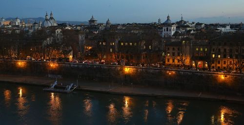 Illuminated buildings by river at night