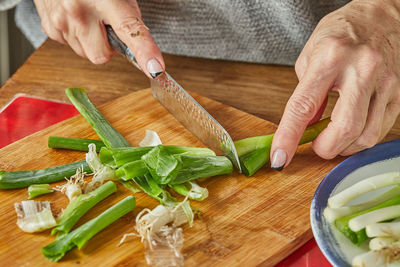 Chef cuts the leek in circles, in the kitchen on wooden board