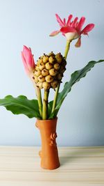 Close-up of flower vase on table against wall