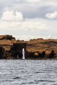 Rock formations by sea against sky