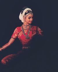 Young woman dancing against black background