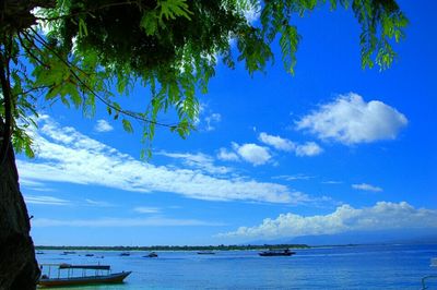 Boats in sea against cloudy sky