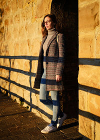 Young woman standing against wall