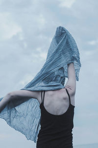 Rear view of woman holding scarf against sky