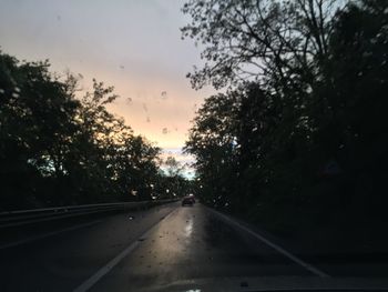 Road amidst trees against sky during sunset