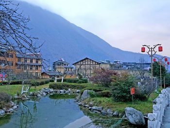 Houses by lake and buildings against sky