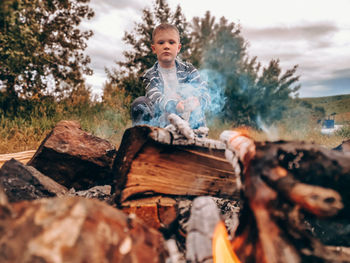 View of boy on wooden log in forest