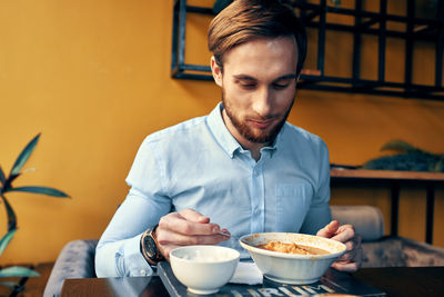 Young man eating food at restaurant