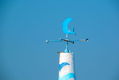 Low angle view of weather vane against blue sky