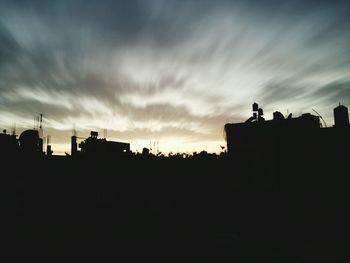 Silhouette built structure against cloudy sky