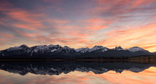 Scenic view of lake by mountains against sky during sunset