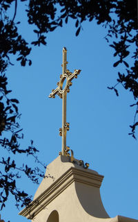 Low angle view of cross by building against clear blue sky