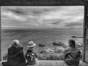 Rear view of people looking at sea against sky