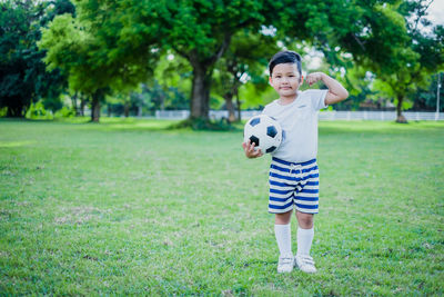 Full length of boy playing soccer on field