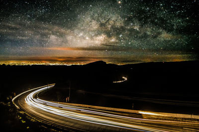 Light trails on road against sky at night