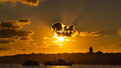 Silhouette boats in sea against sky during sunset