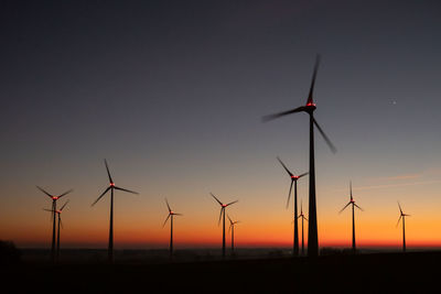 Low angle view of windmills against clear sky during sunset