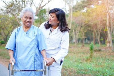 Portrait of senior female patient with doctor using mobility walker outdoors