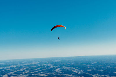 Person paragliding flying against clear sky