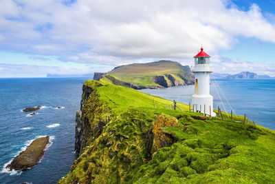 Lighthouse by sea against sky