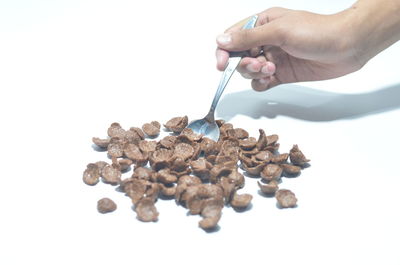 Midsection of person holding ice cream cone against white background