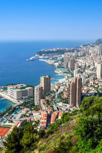 High angle view of buildings and sea against clear blue sky