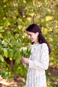 Young woman standing against plants