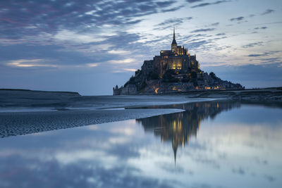 View of building by beach against cloudy sky