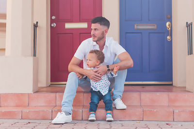 Dad and toddler sitting on the steps watching the street