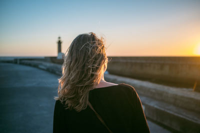 Rear view of woman on promenade against sky during sunset