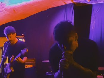 Boy standing against multi colored lights