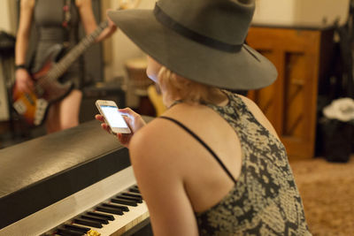 Young woman looking at her cell phone while seated at a piano