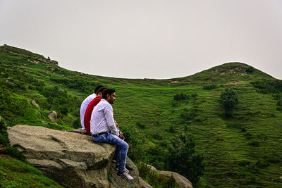 Rear view of people sitting on edge of mountain