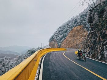 Road by mountain against sky during winter