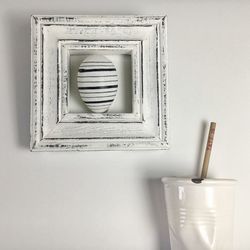 Easter egg framed on white wall by metal container