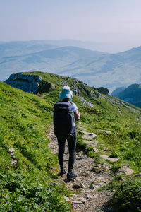 Rear view of man looking at mountains against sky