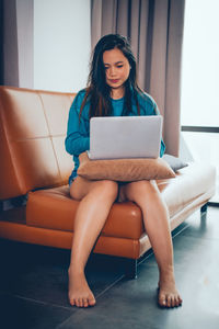 Full length of young woman using mobile phone