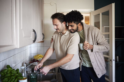 Gay couple washing dishes and drinking coffee at home