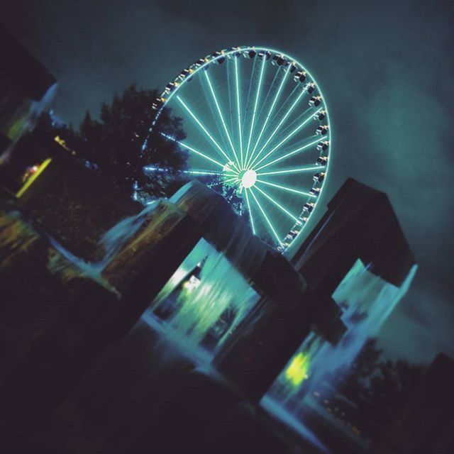 low angle view, illuminated, night, arts culture and entertainment, sky, built structure, circle, ferris wheel, silhouette, amusement park, architecture, tree, lighting equipment, no people, outdoors, reflection, glowing, amusement park ride, multi colored, light - natural phenomenon