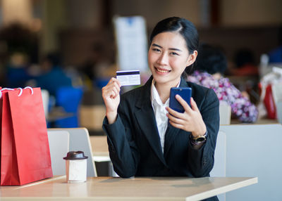 Young woman using mobile phone at table