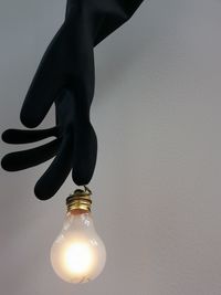 Close-up of illuminated light bulb hanging on wall